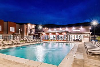 A swimming pool area with lounge chairs and a building in the background.